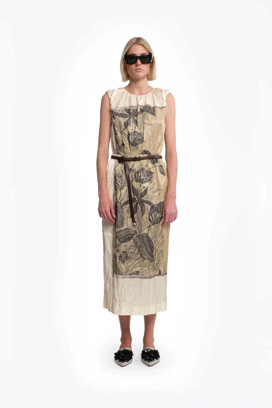 Woman wearing a sleeveless dress with floral pattern on a white background.