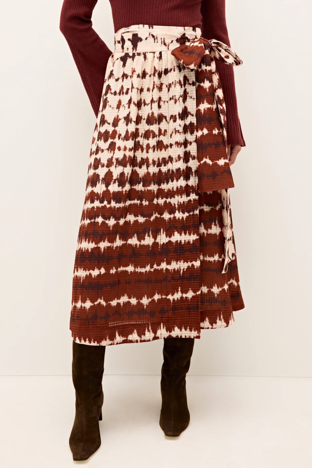 Woman wearing a patterned skirt with a white background.