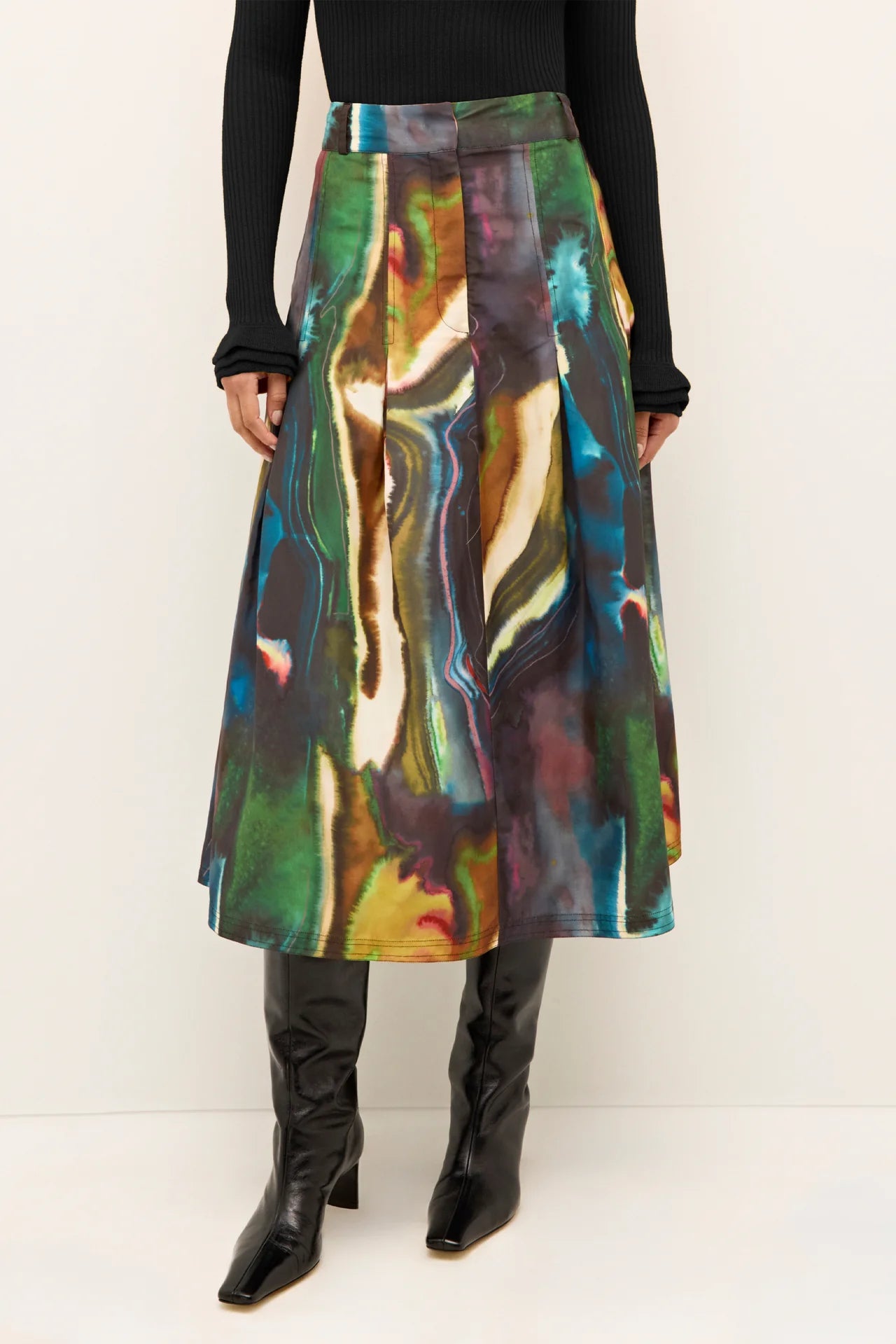 Woman wearing a colorful abstract patterned skirt with black boots on a white background.