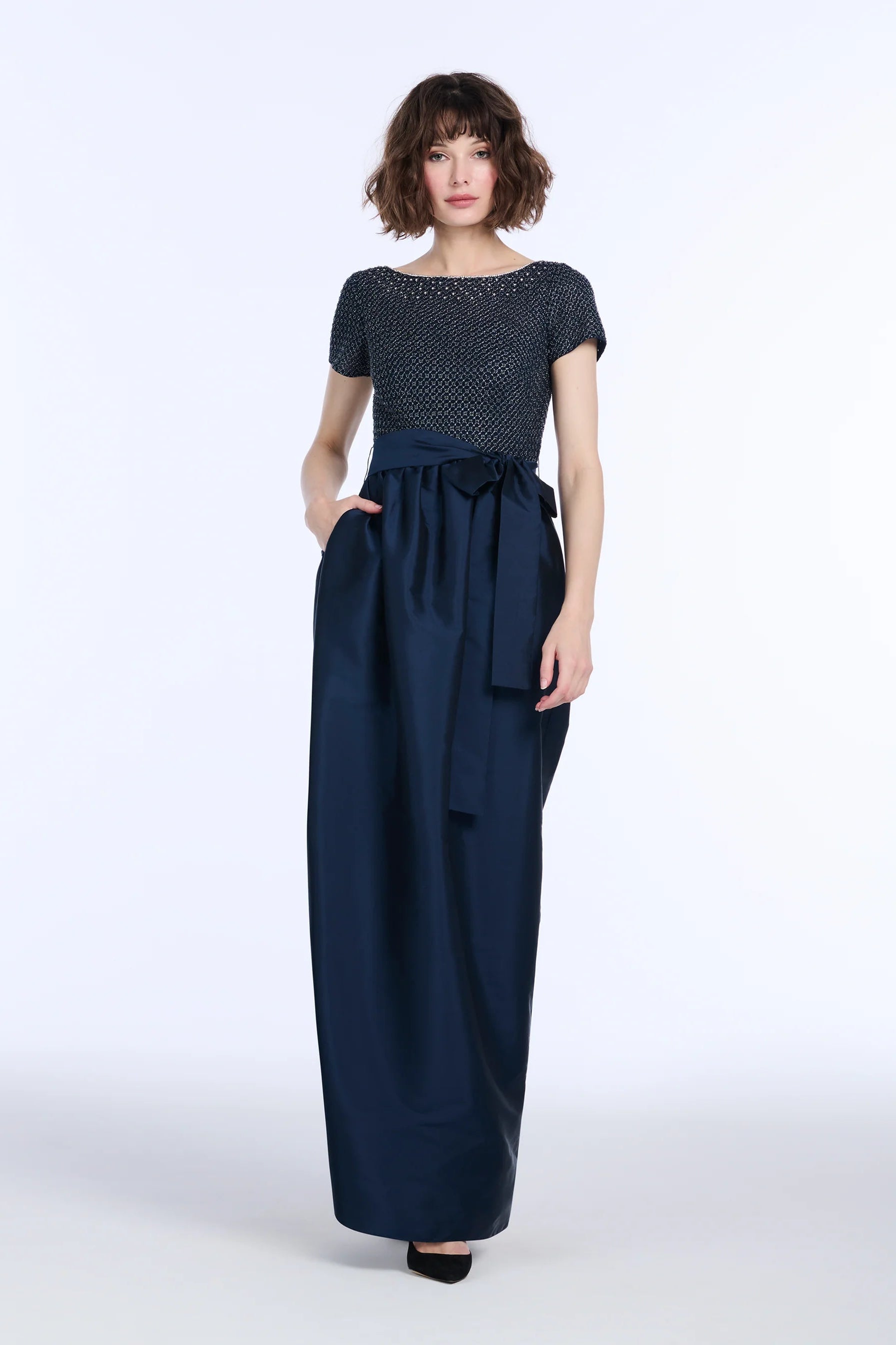 Woman wearing a navy dress with a white background.