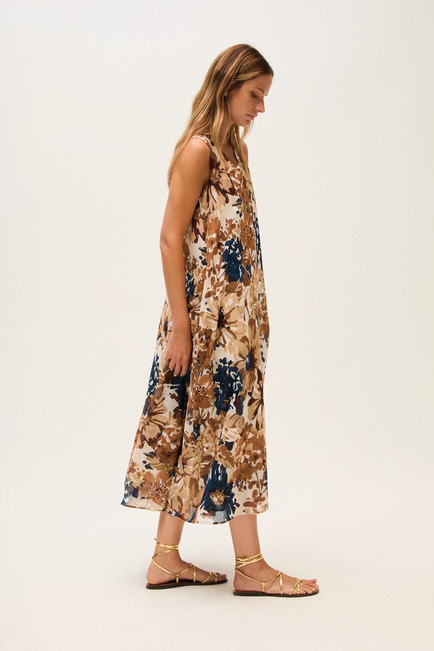 Side view of a woman wearing a floral dress on a white background.
