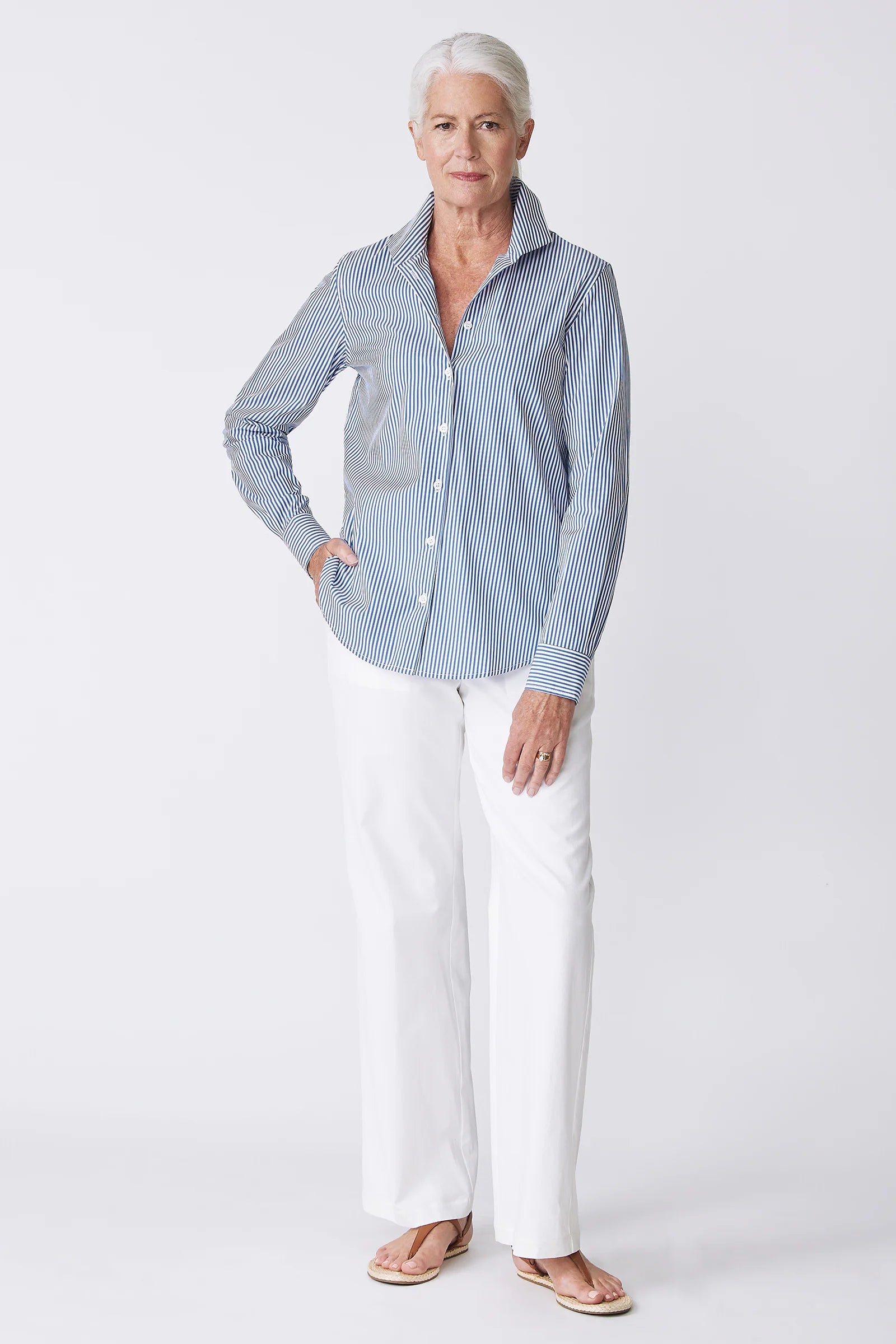 Woman wearing a blue striped shirt and white pants on a white background