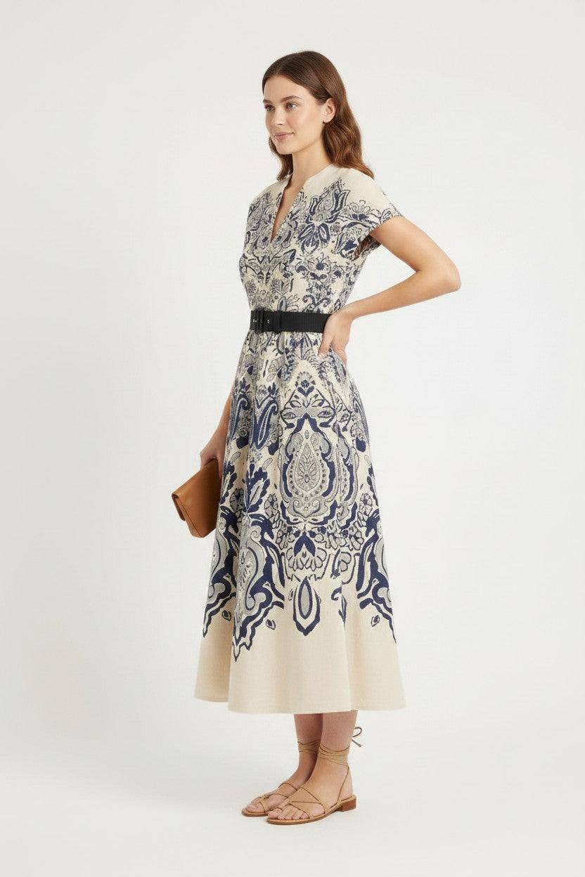 Woman wearing a patterned dress with a belt on a white background.