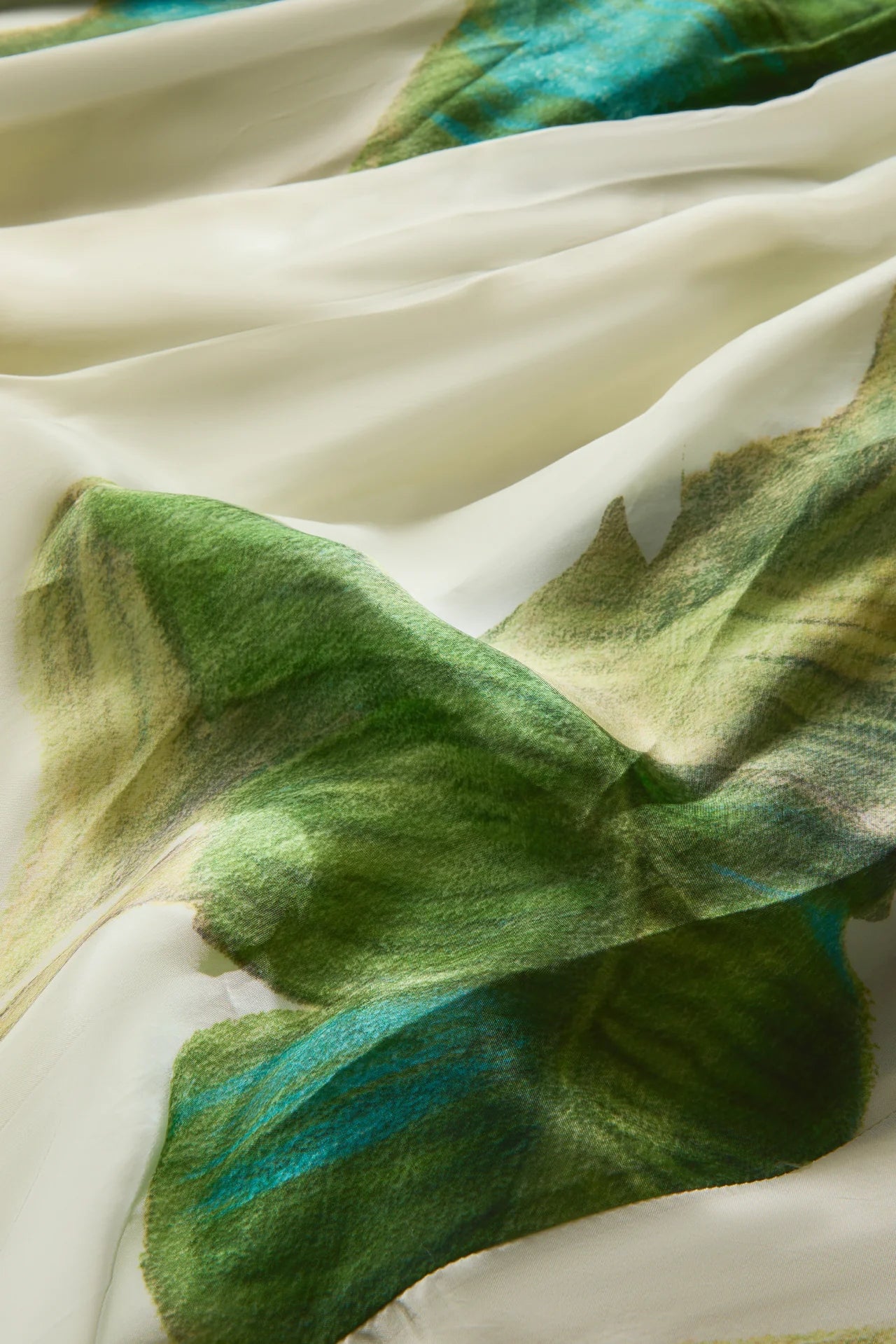 Close-up of fabric with green and blue leaf patterns.
