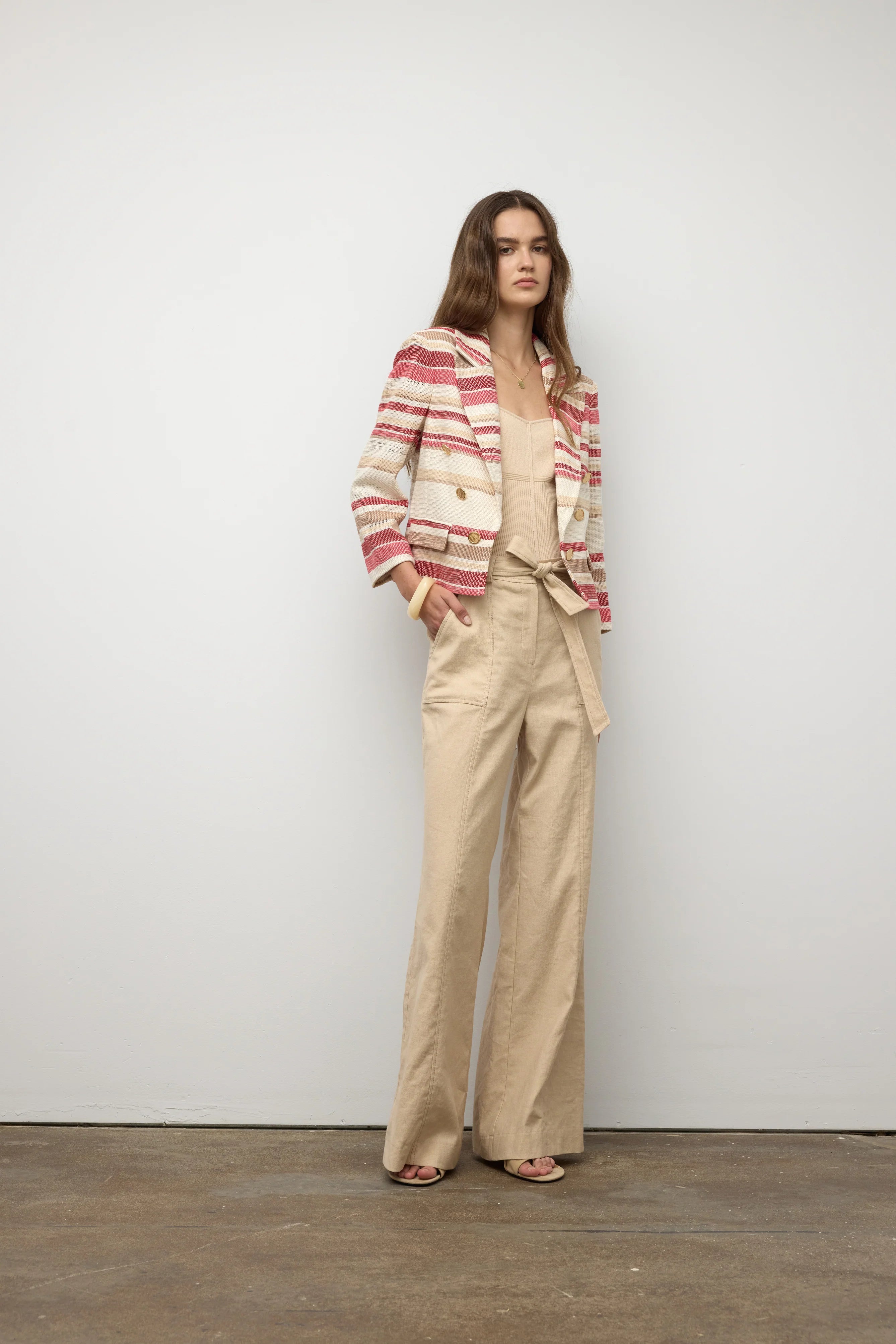 Woman wearing a striped blazer and beige pants against a plain background.