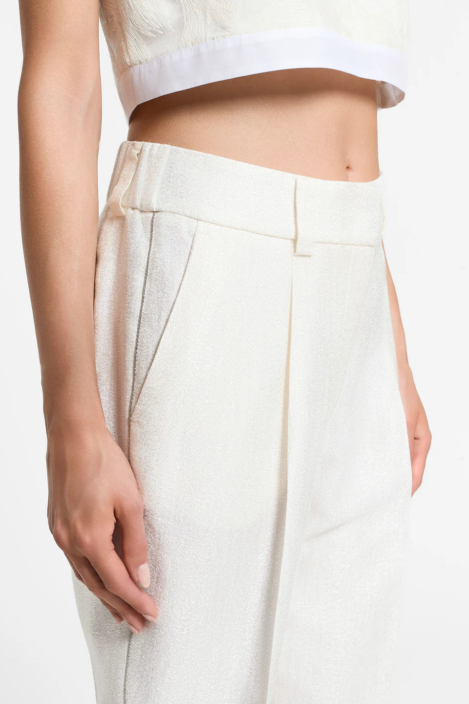Close-up of a woman wearing white pants with sparkle detailing on the side.