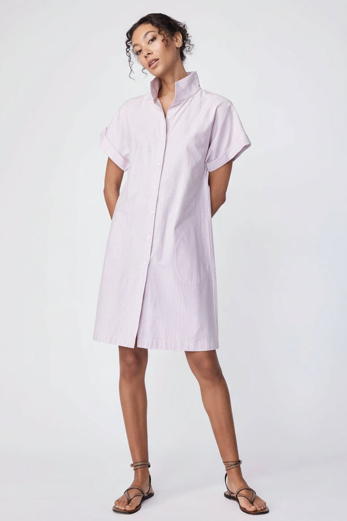 Woman wearing a light pink dress with stripes on a white background.