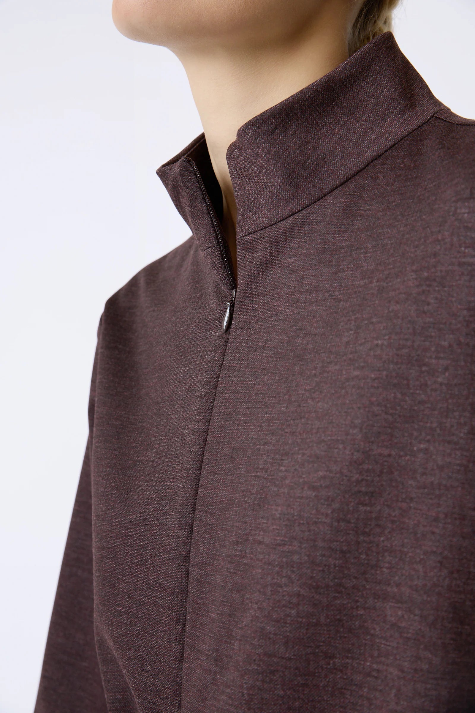 Close-up of a person wearing a burgundy heathered quarter-zip dress with a stand collar, showing the neck, lower face, and upper chest against a plain light background.
