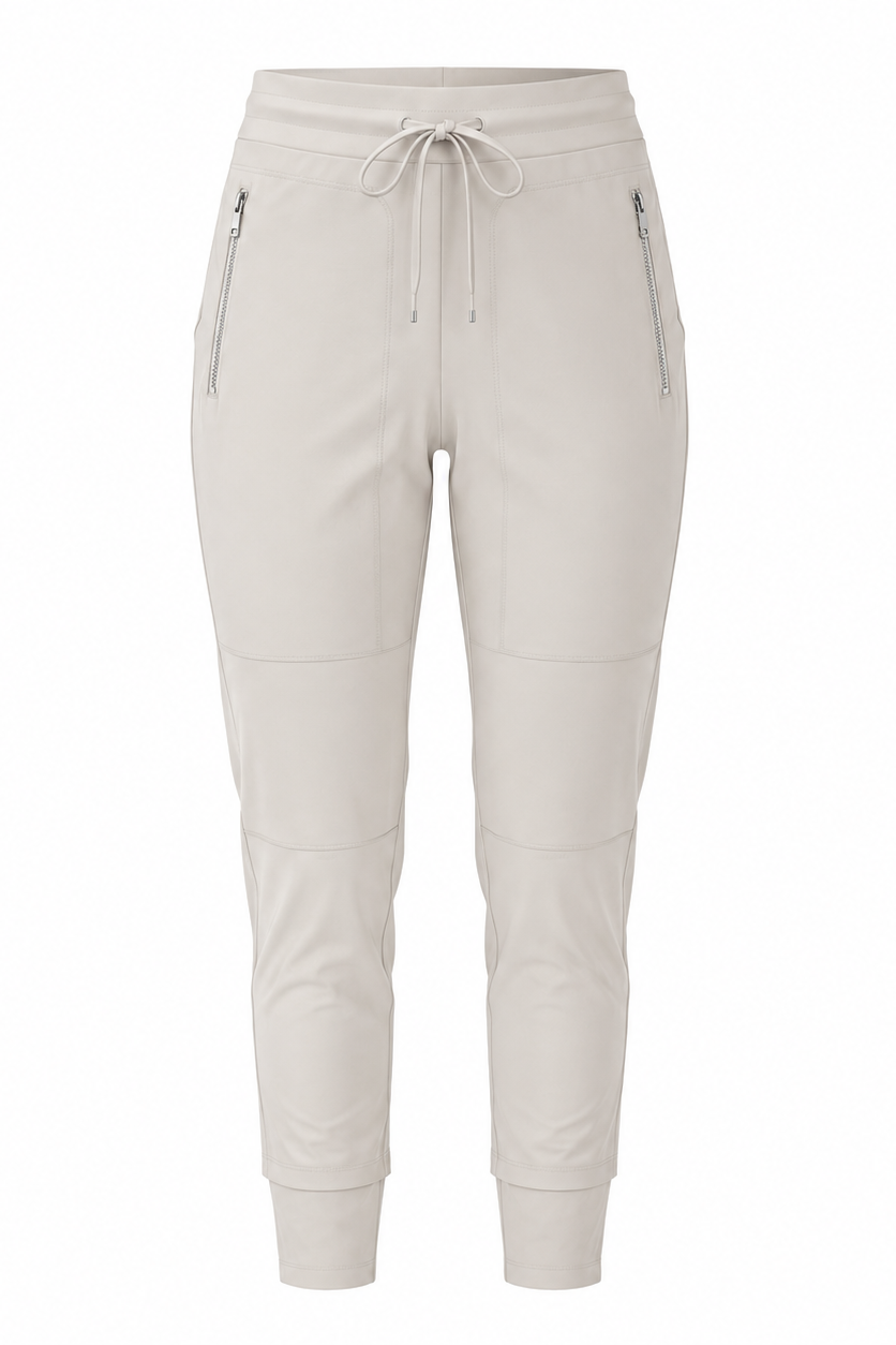 A pair of light beige cropped jogger pants with an elastic drawstring waist, zippered side pockets, and ribbed ankle cuffs, shown against a plain white background.