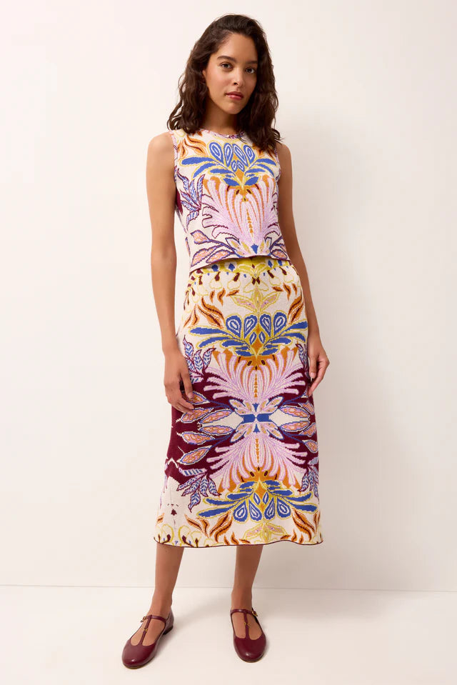 Woman wearing a colorful sleeveless tank top and skirt with a pattern on a white background.