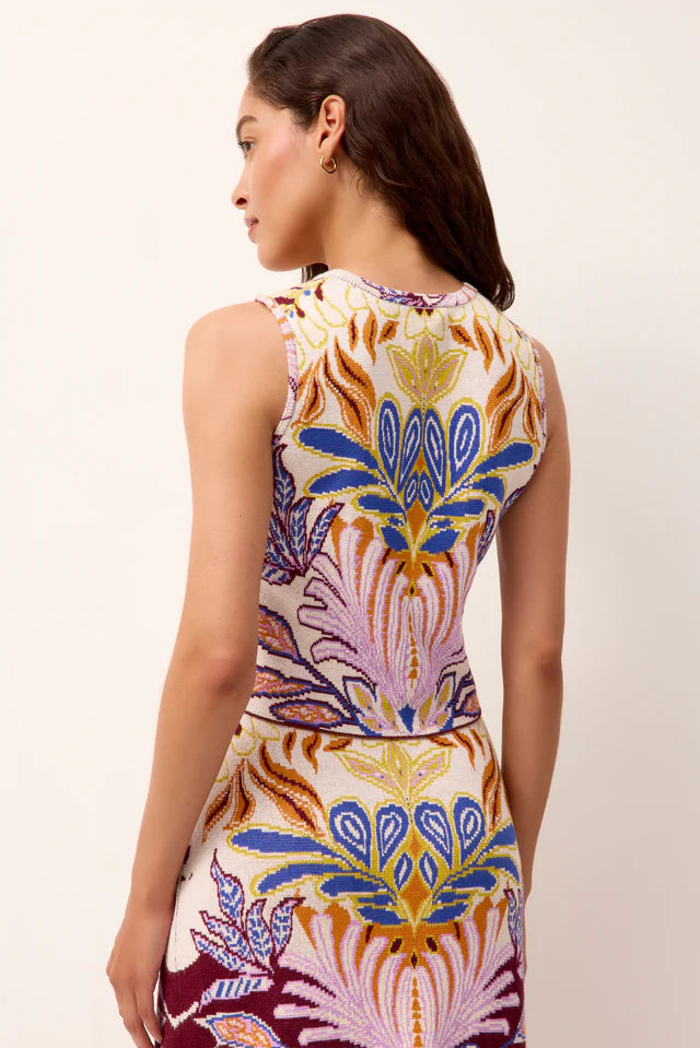 Woman wearing a sleeveless top and skirt with a colorful abstract pattern on a plain background.