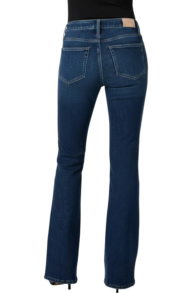 Back of a woman wearing blue jeans on a white background.