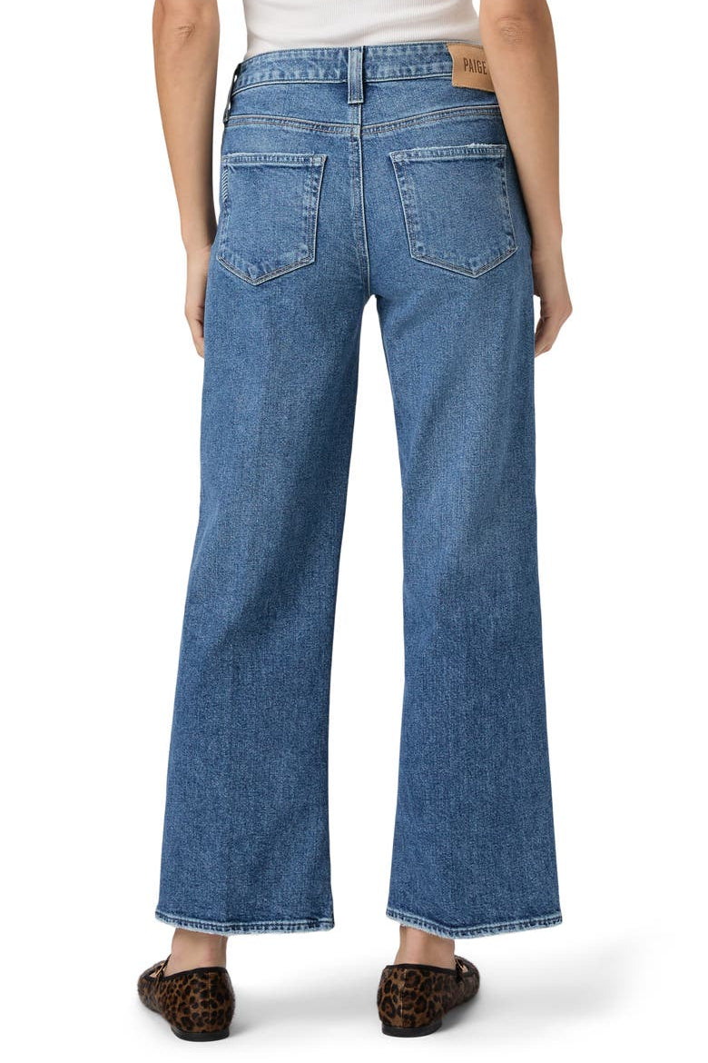 Back of a woman wearing blue jeans on a white background.