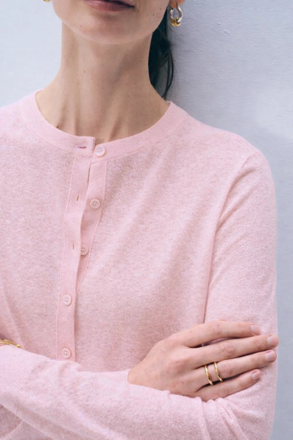 Close-up of a woman wearing a light pink cardigan with a neutral background.