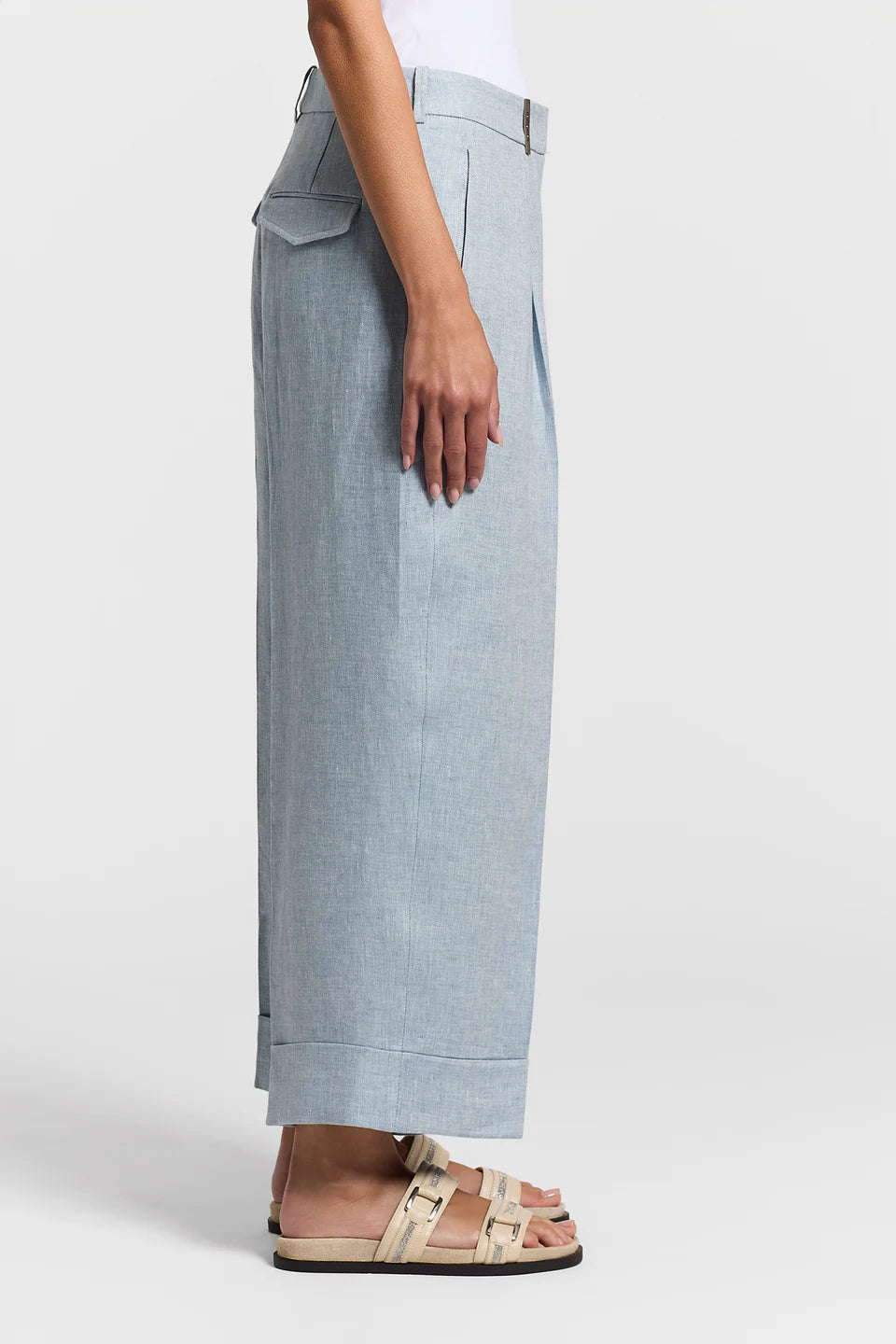 Side view of a woman wearing blue pants on a white background.