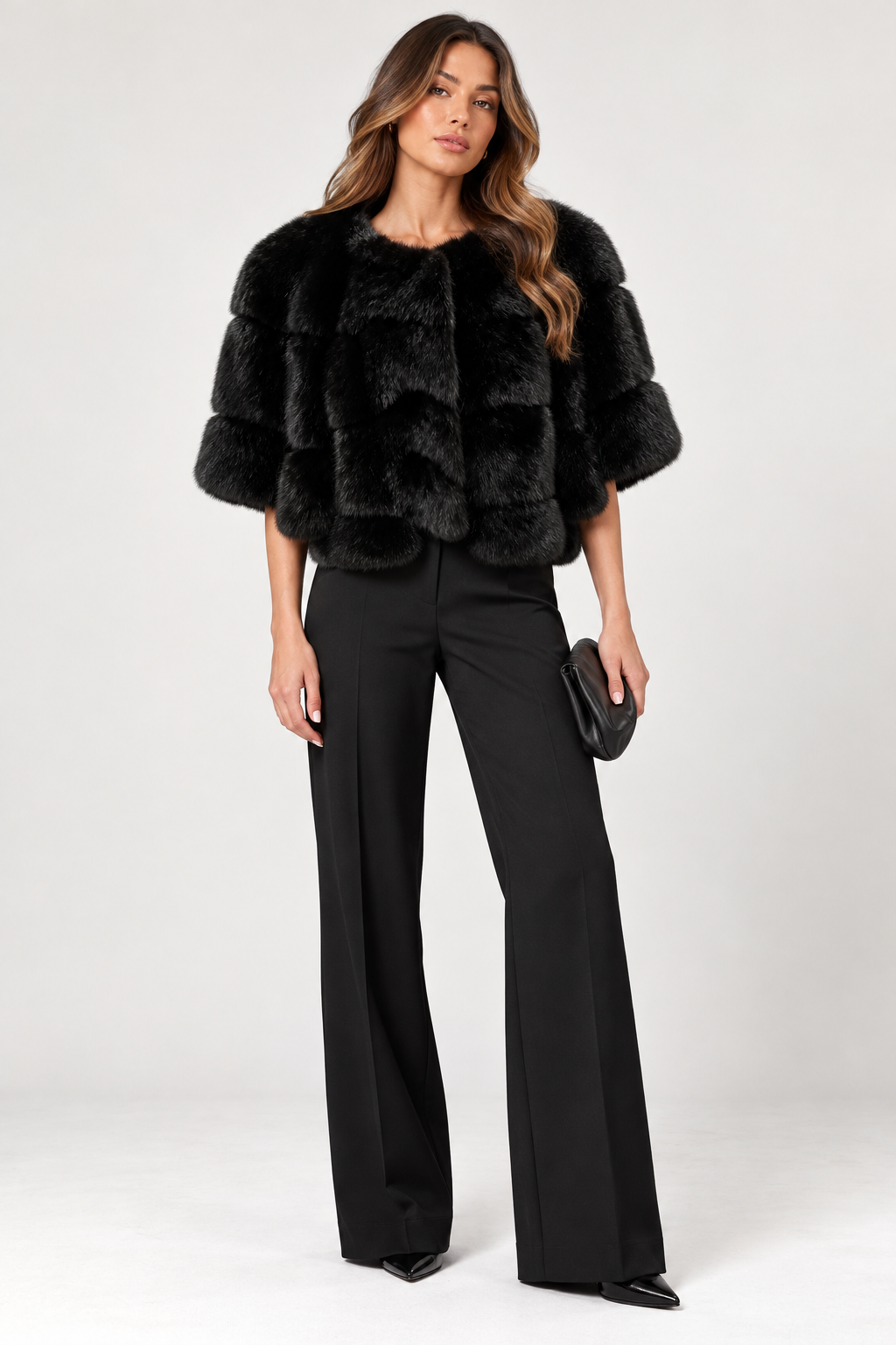 Front-facing full-length model wearing the Suprema Black Mink Fur Cropped Capelet, featuring luxurious genuine black mink fur, a rounded neckline, voluminous elbow-length sleeves, layered fur panels, and a softly scalloped hem. Styled with tailored black wide-leg trousers, pointed-toe heels, and a black clutch against a neutral studio background.