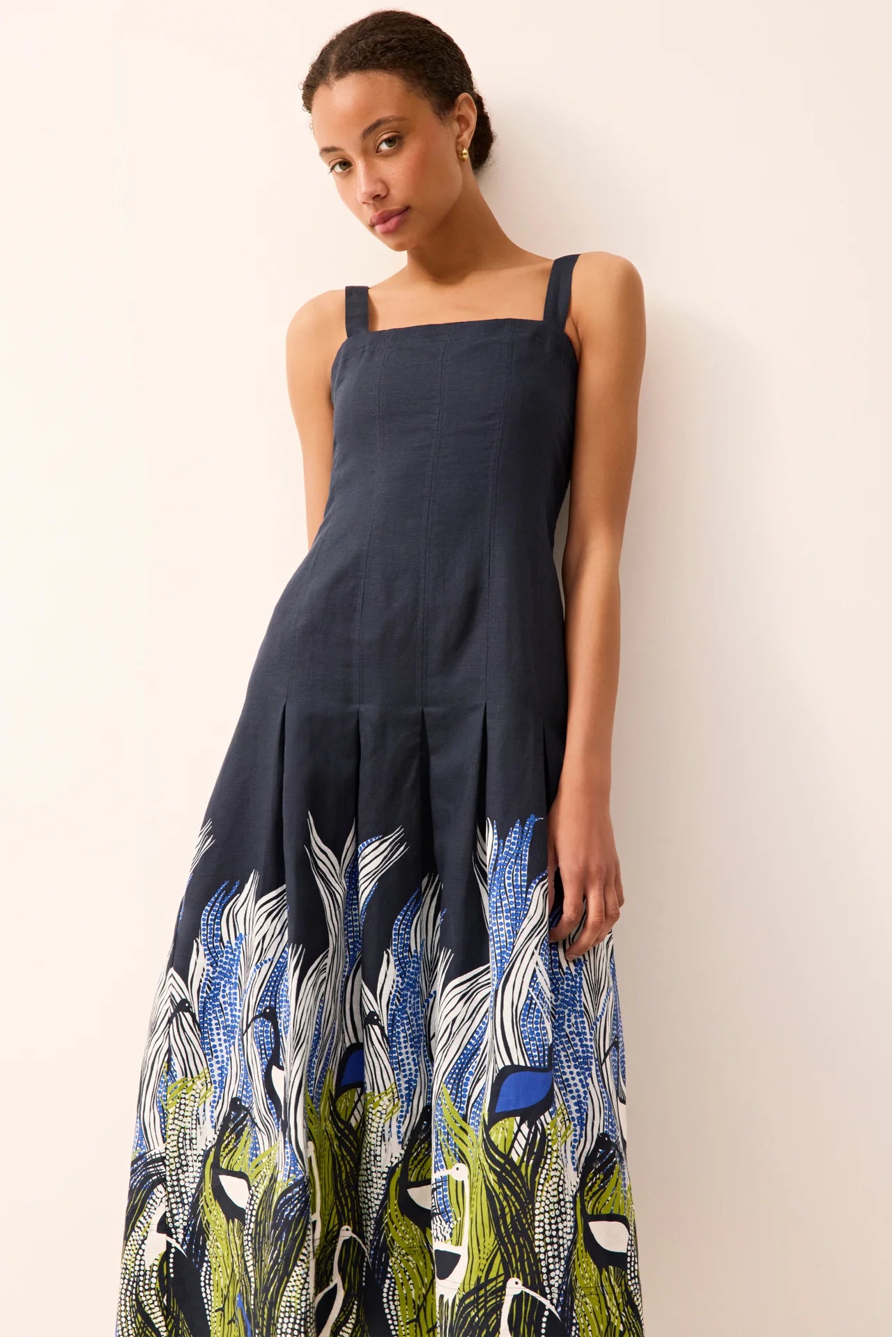 Woman wearing a navy dress with a colorful peacock pattern on a white background.
