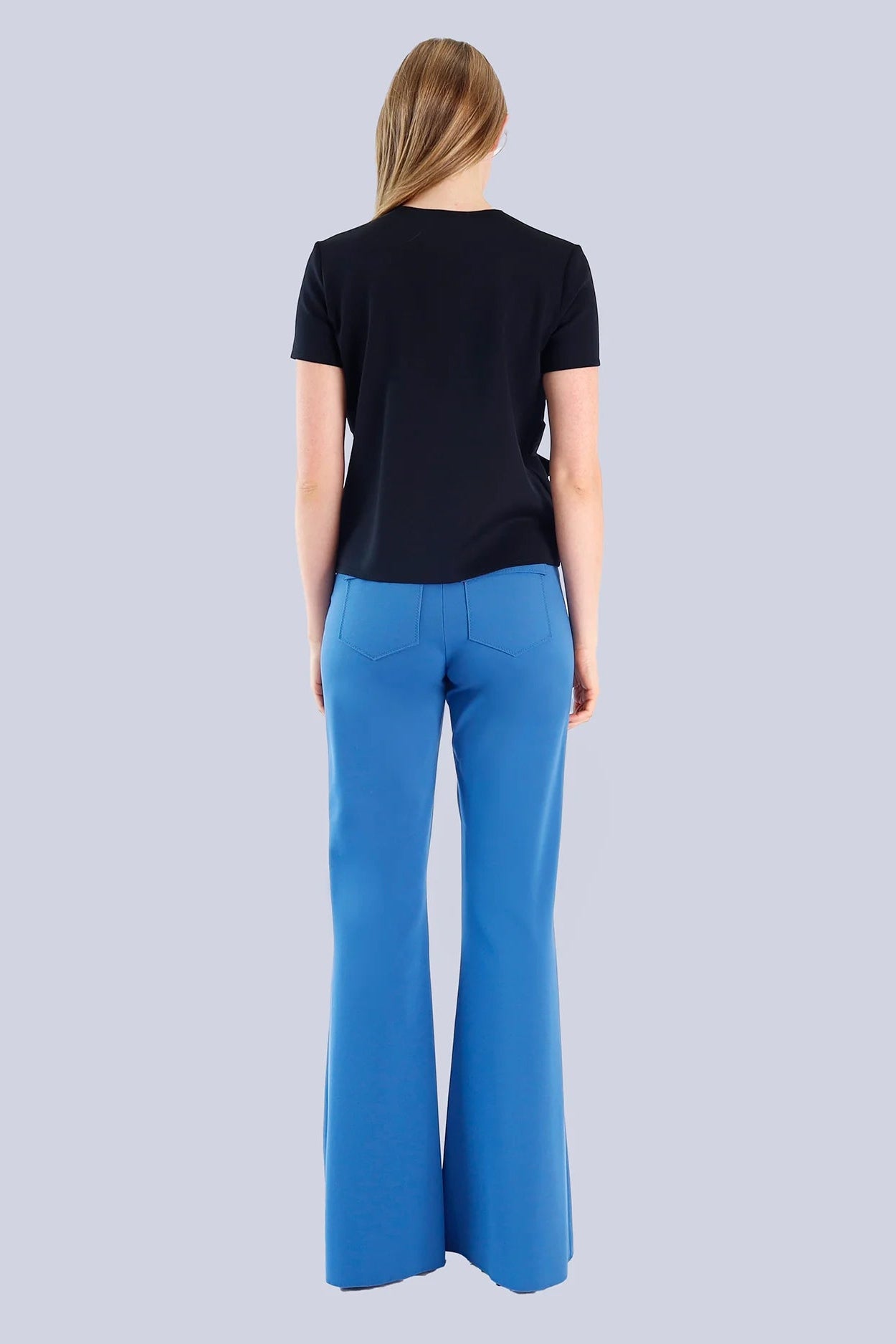 Person wearing a black top and blue pants on a light gray background.