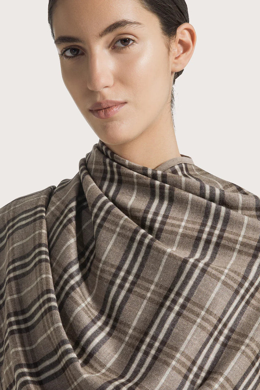 Woman wearing a plaid shawl on a plain background.