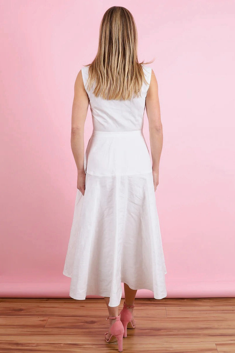 The back of a woman wearing an off-white dress against a pink wall.