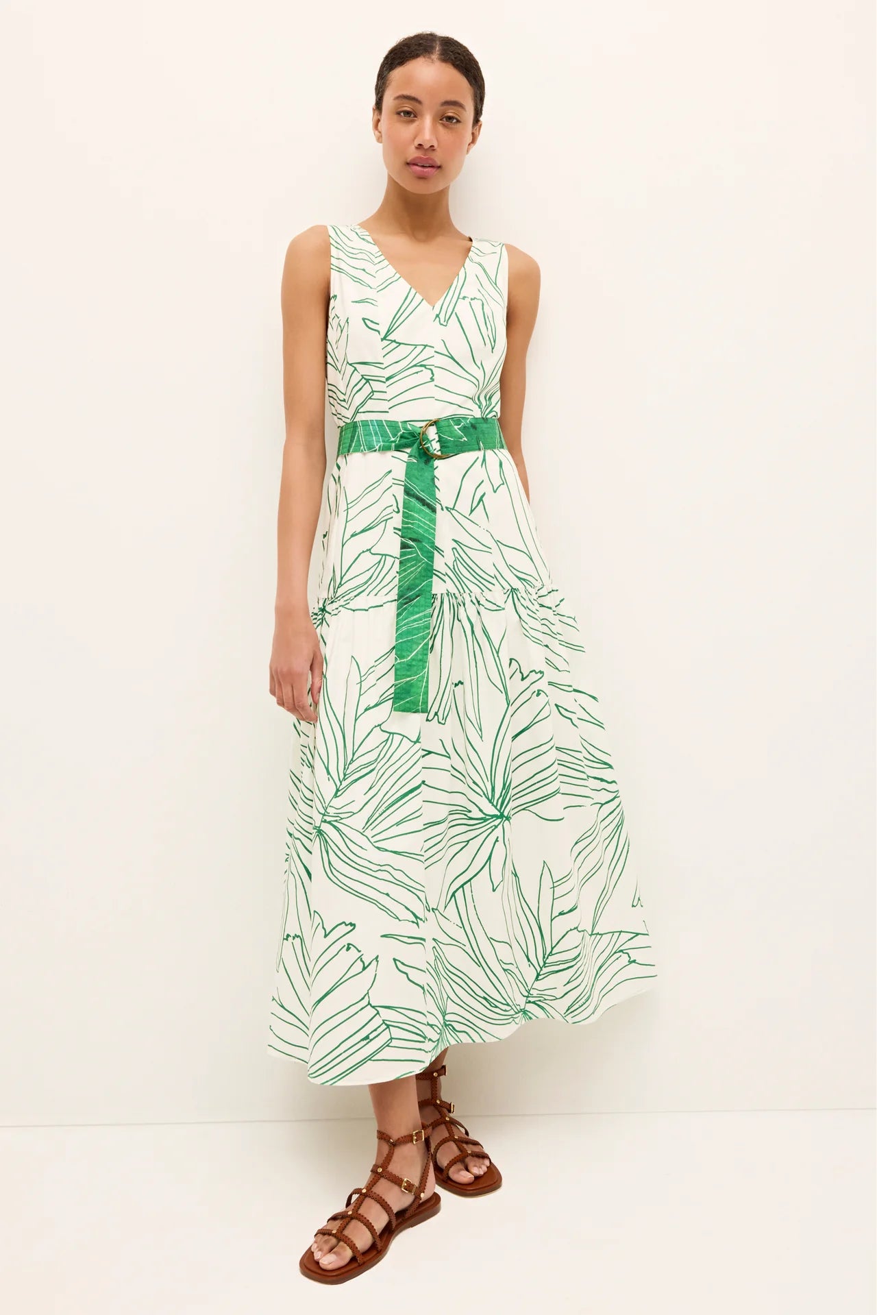 Woman wearing a green and white leaf-patterned dress with a belt on a white background