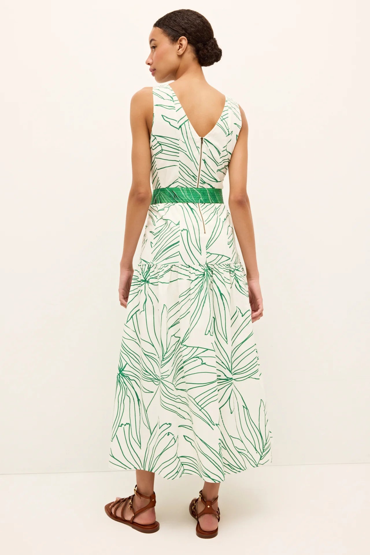Woman wearing a green and white leaf-patterned dress on a white background.