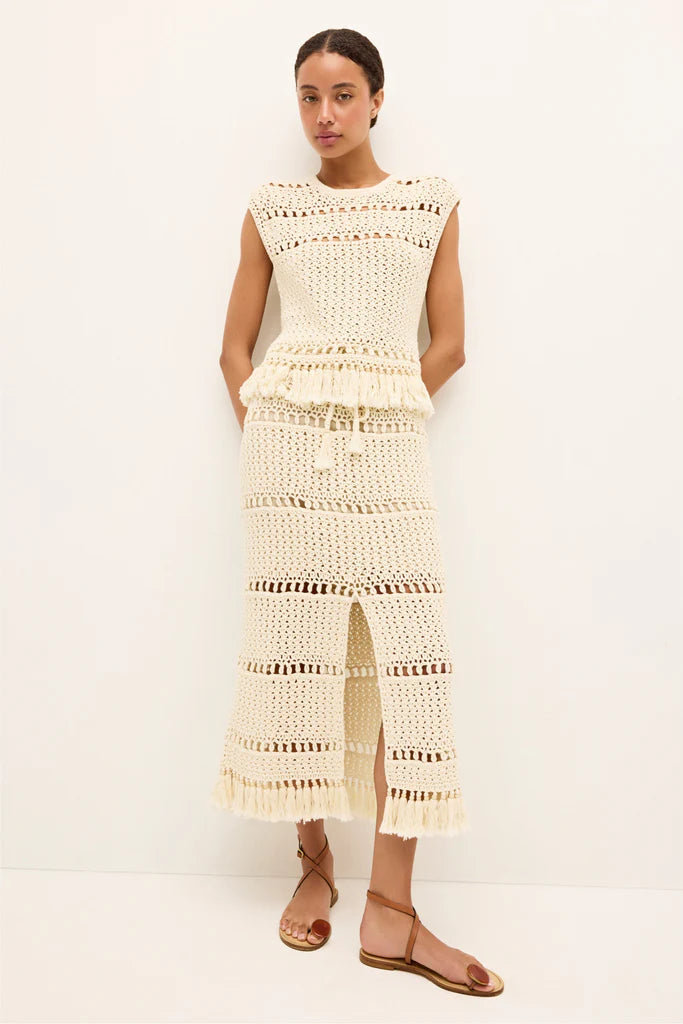 Woman wearing a beige crochet top and skirt on a white background.