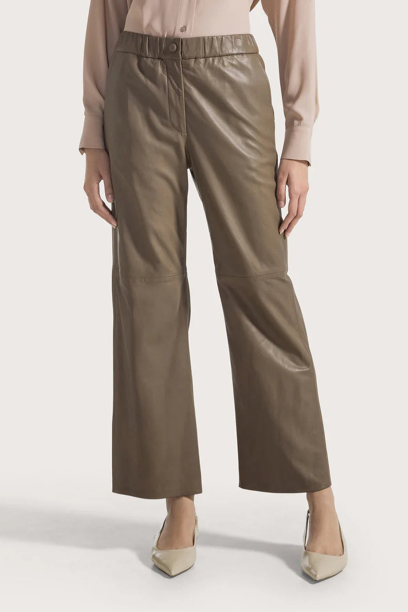 Woman wearing taupe pants on a white background.