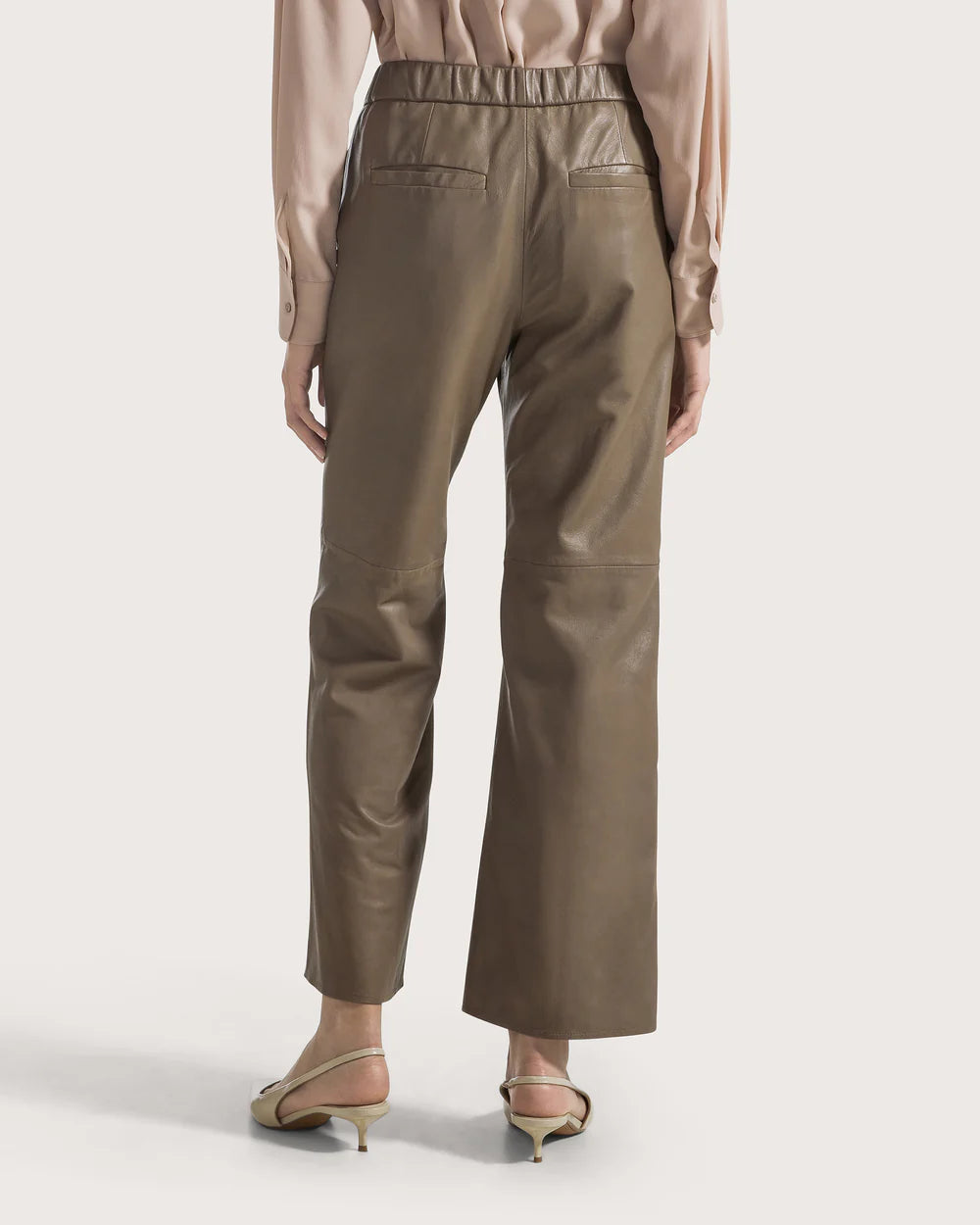 Woman wearing taupe pants on a white background.