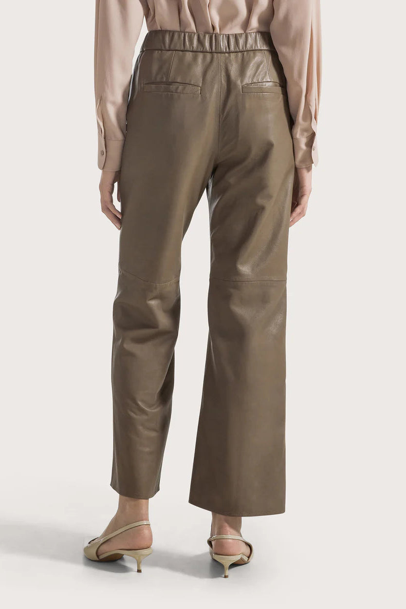Woman wearing taupe pants on a white background.