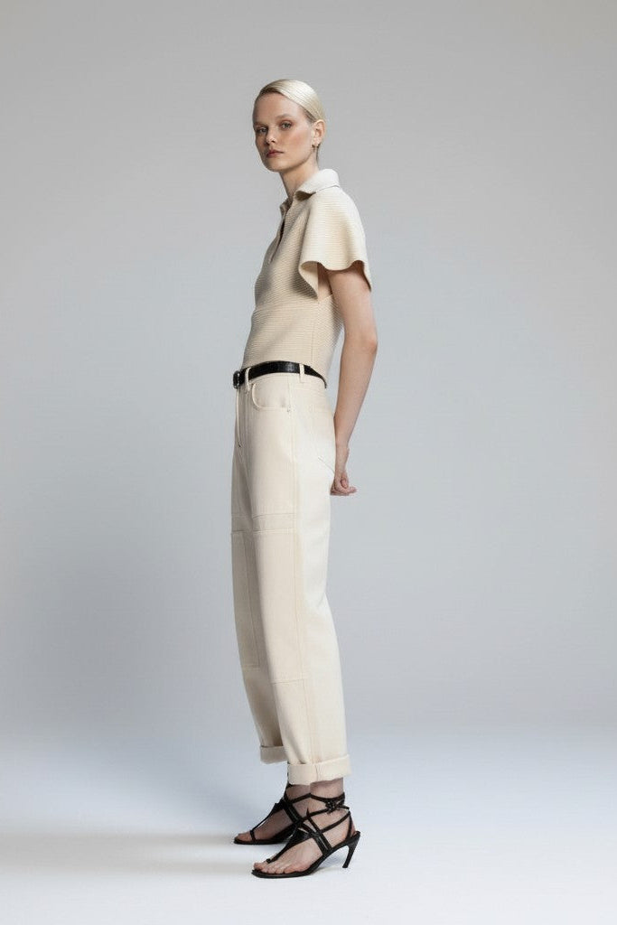 Woman wearing a beige outfit with a belt on a plain background.