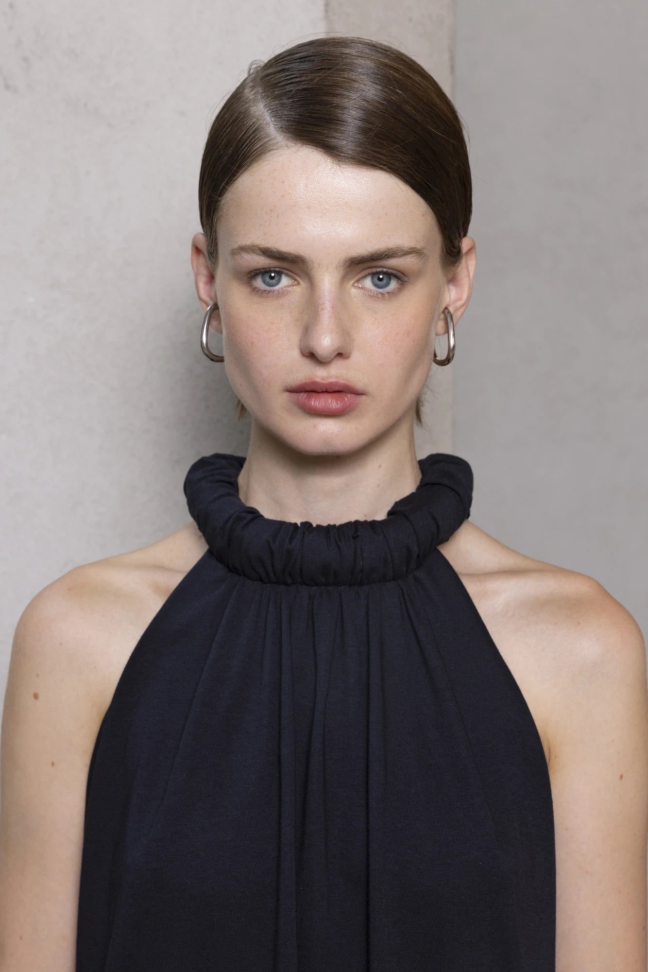 Close-up of a woman wearing a black maxi dress wit ha razor back rolled neck silhouette.