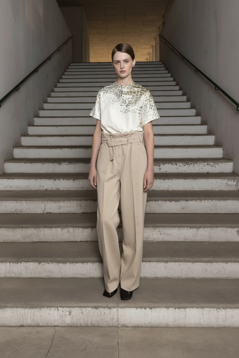 Woman in a white top and beige pants standing on a staircase.