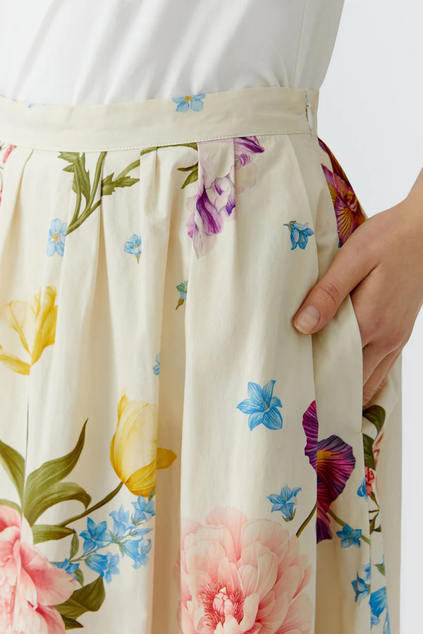 Close-up of a floral skirt with pockets and a colorful pattern on a plain background.