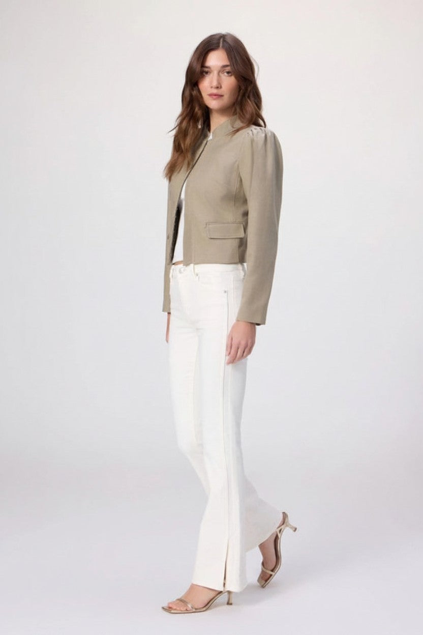 Woman wearing a beige blazer and white jeans on a white background.