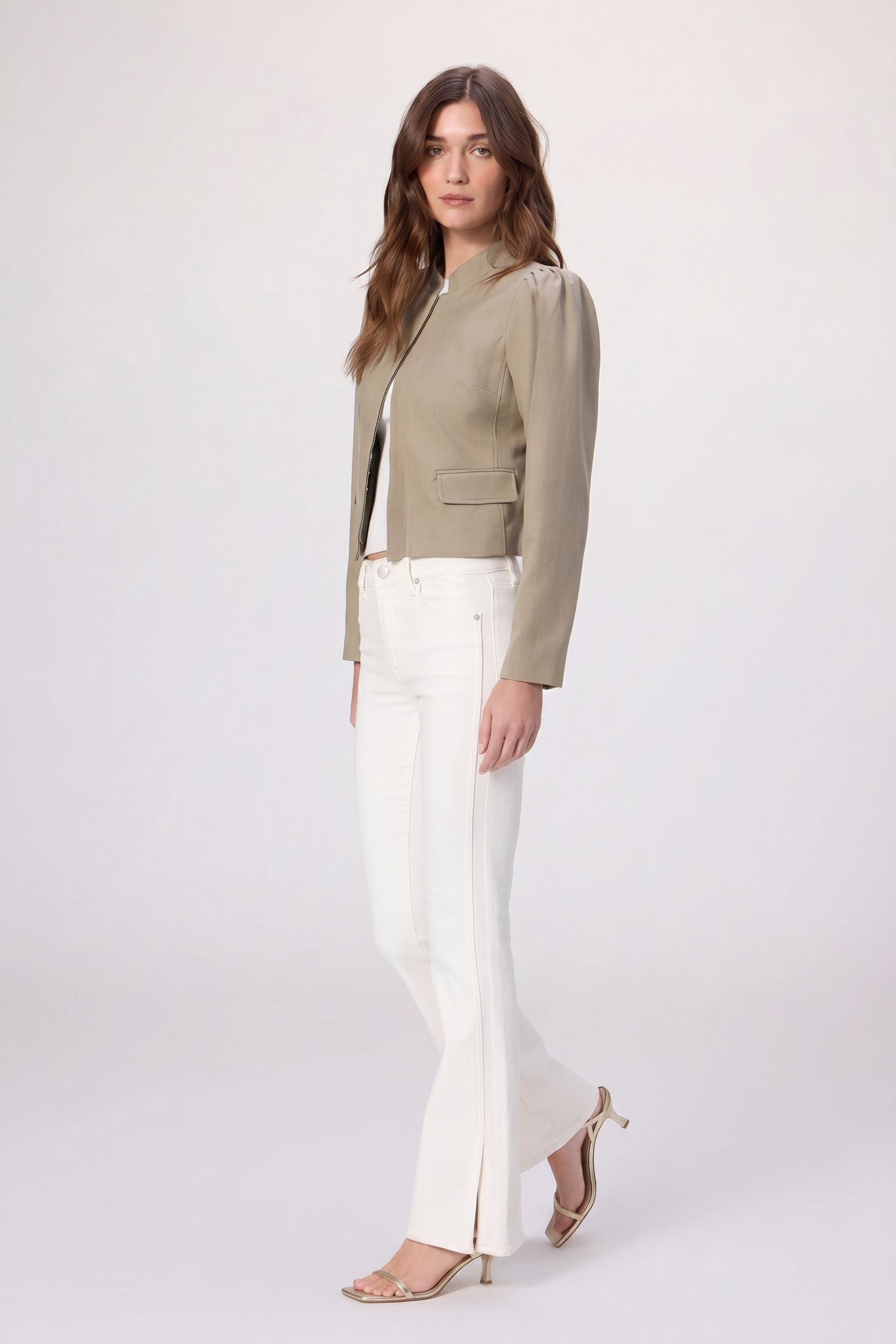 Woman wearing a beige blazer and white pants on a white background,
