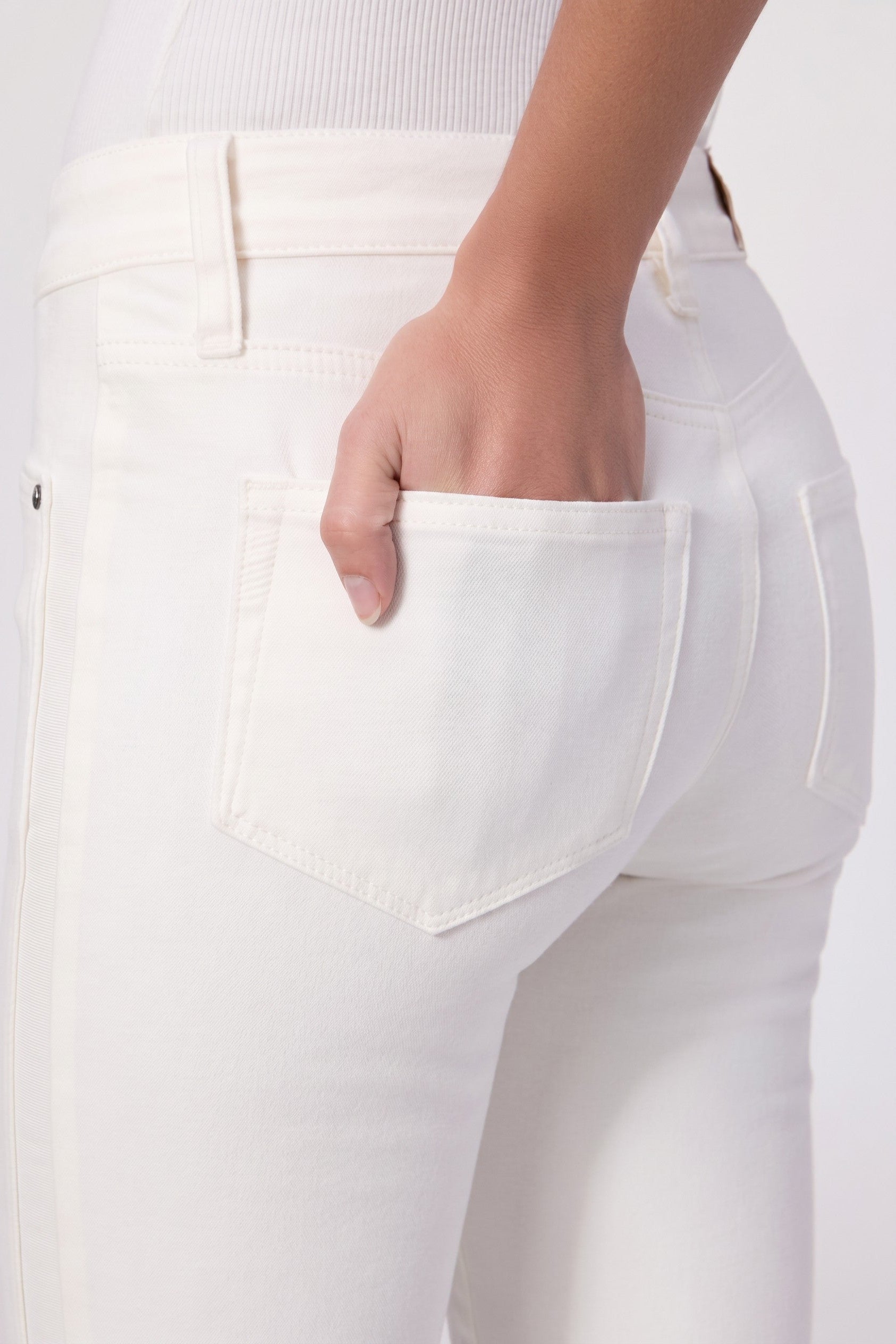 Close-up of a person wearing white pants with a pocket.