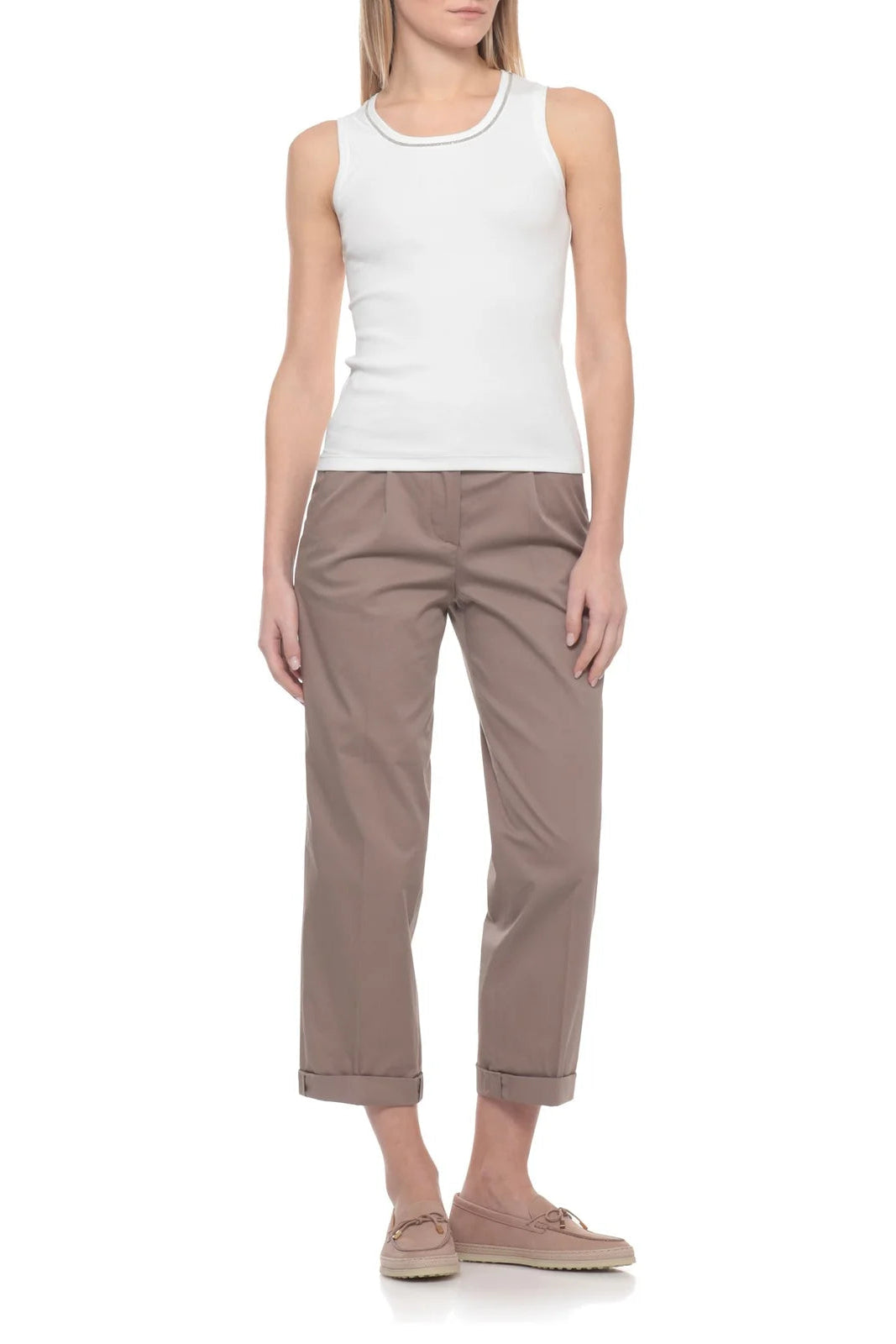 Woman wearing a white sleeveless top with a sparkle trim neckline and brown pants on a white background.