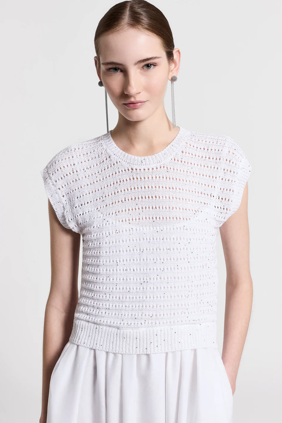 Close-up of a woman wearing a white dress against a plain background.