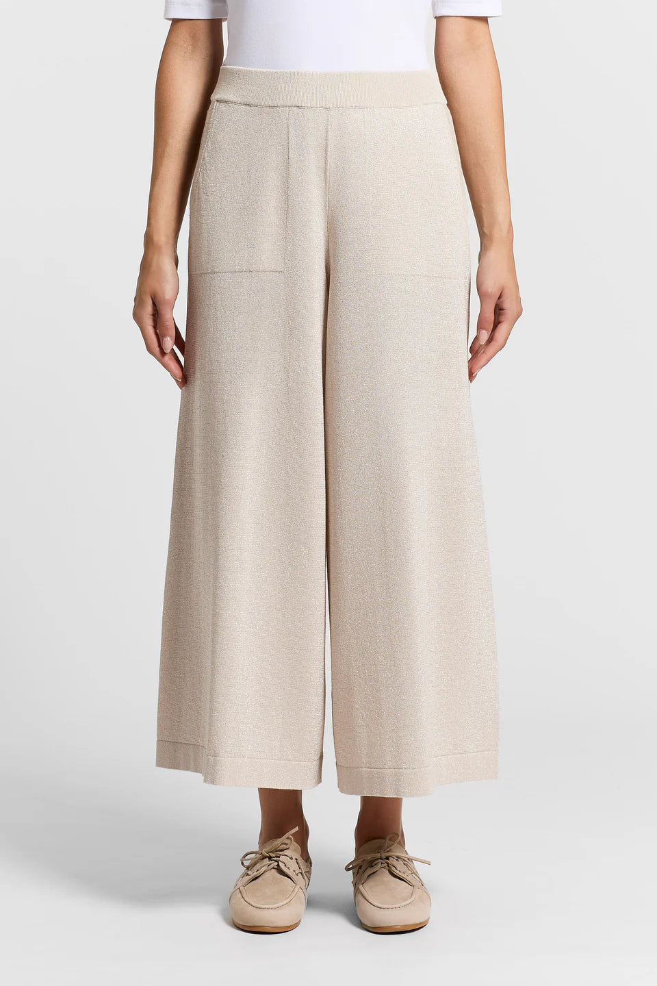 Close-up of a woman wearing beige wide-leg pants on a white background.