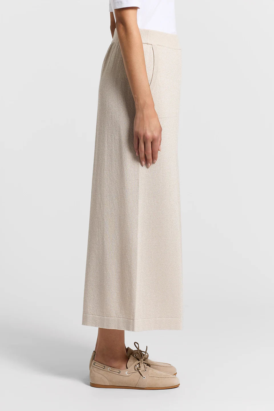 Side view of a woman wearing beige pants on a white background.