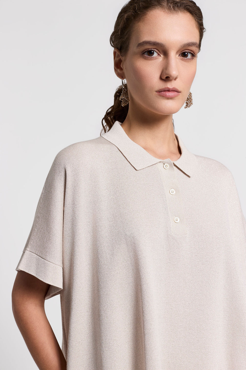 Close-up of a woman wearing a beige polo shirt against a light gray background.
