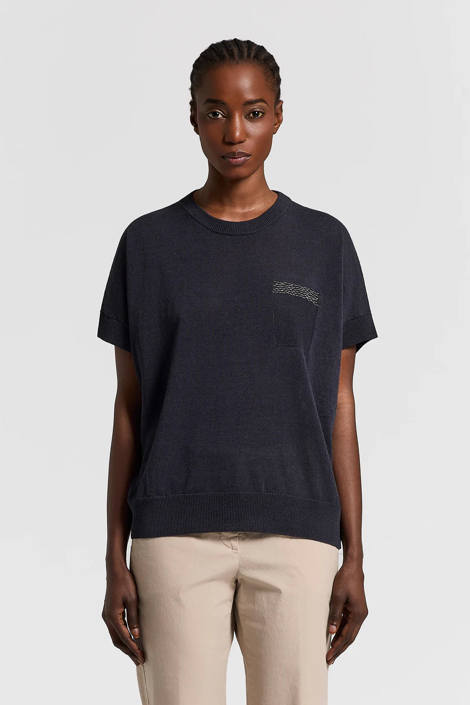 Woman wearing a dark blue t-shirt with a logo on a white background.