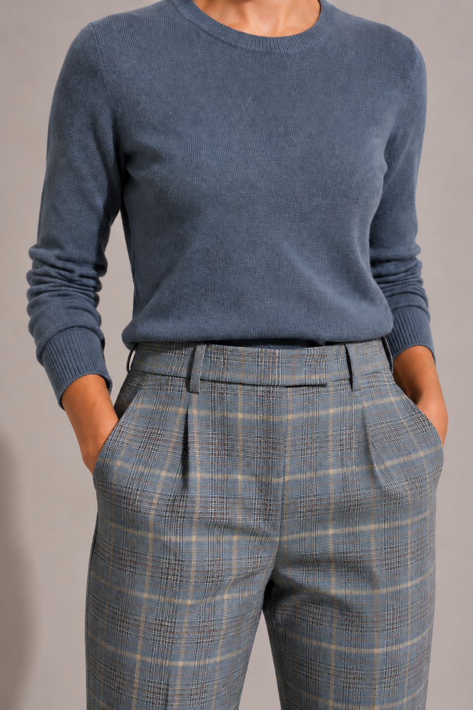 Close-up of the blue-gray plaid Maura Pant on a model, highlighting the extended waistband, belt loops, front pleats, and beige and brown plaid detailing.
