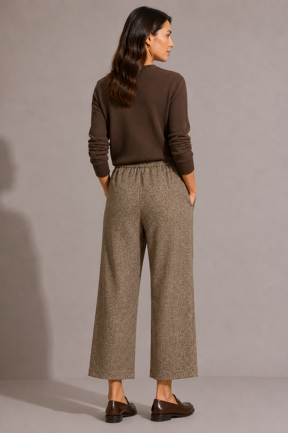 Model wearing the QL2 Tilde Wool Pant in brown mélange with a dark brown sweater and loafers, shown from the back.