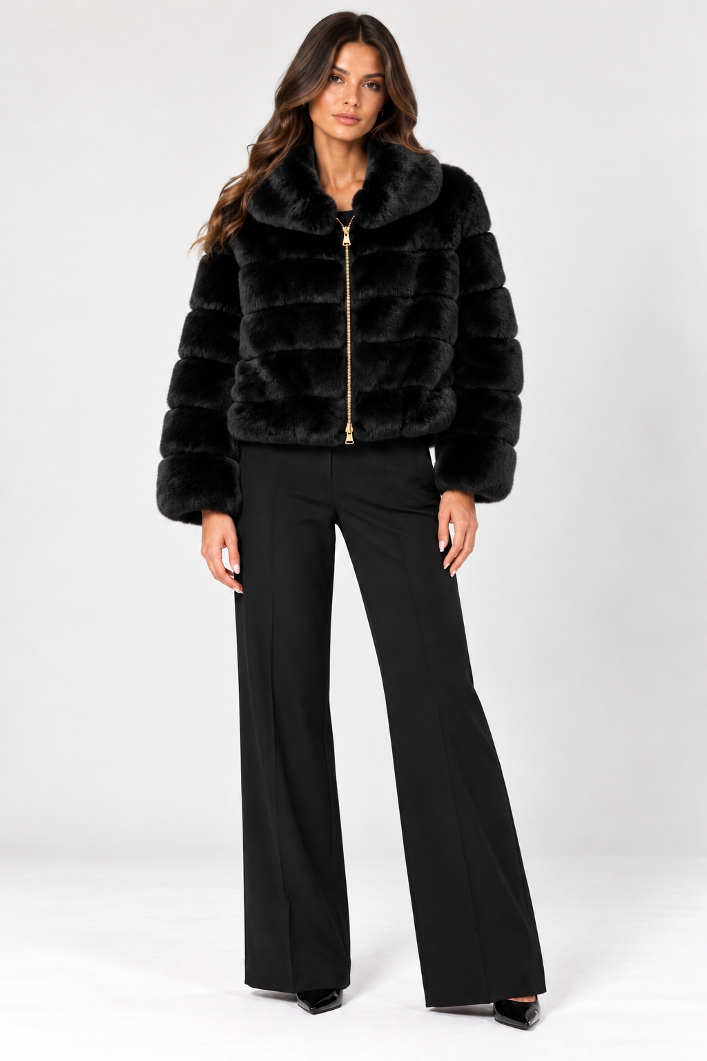 Front-facing model wearing the Suprema Black Rex Rabbit Fur Bomber Jacket, featuring plush horizontal fur panels, an oversized fold-down collar, long sleeves, and a gold-tone two-way zipper. Styled with tailored black wide-leg trousers and pointed-toe heels against a neutral studio background.