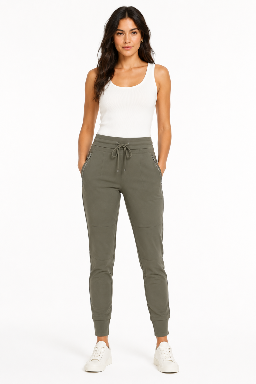 A woman modeling a pair of olive green jogger pants with a drawstring waist, paired with a white tank top and white sneakers, against a plain white background.