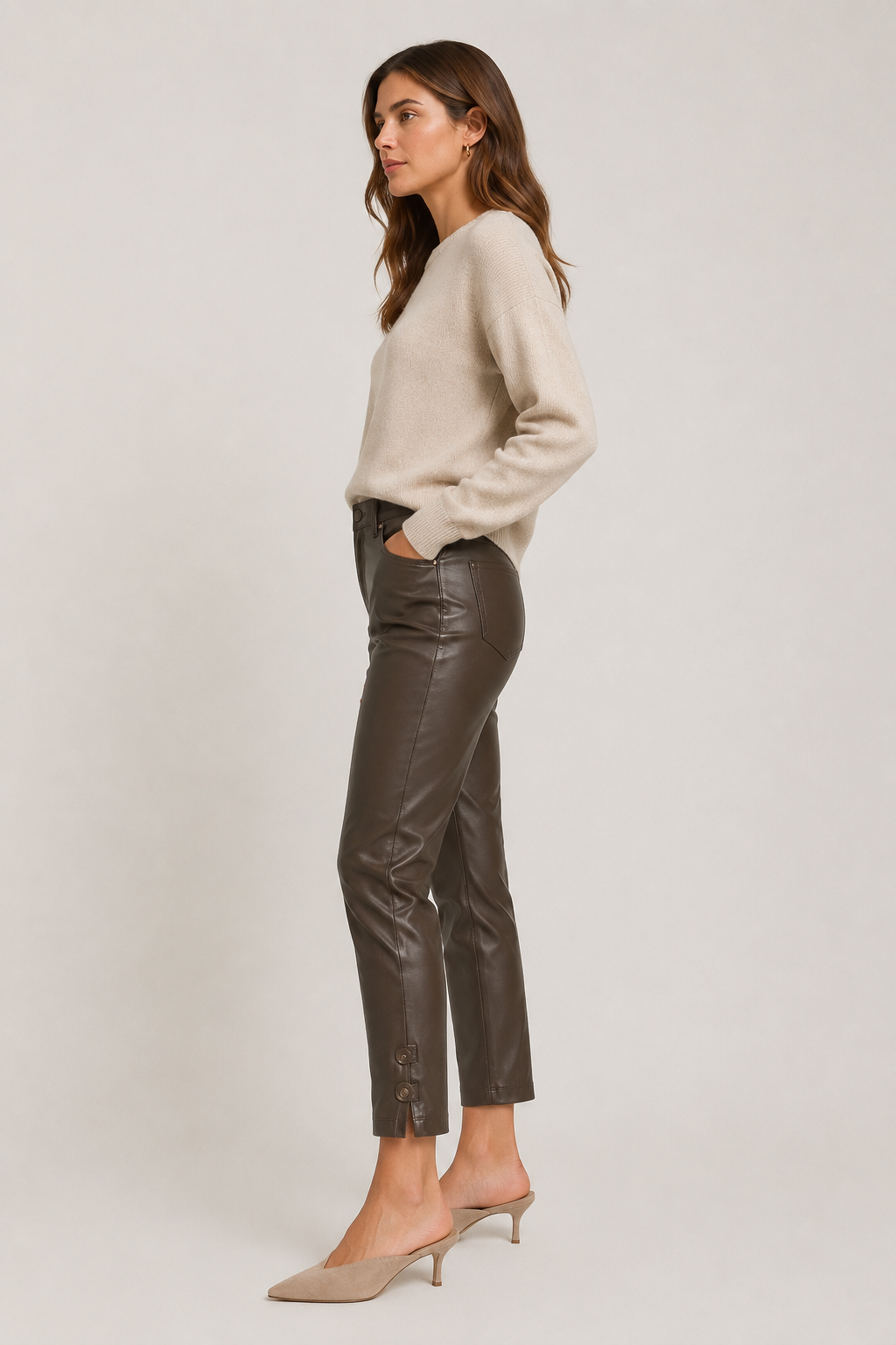Side view of model wearing dark brown Raffaello Rossi Ronija 7/8 vegan leather pants, showing the slim cropped fit and buttoned ankle detail.