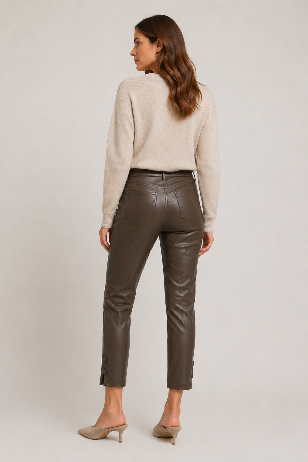 Back view of model wearing dark brown Raffaello Rossi Ronija 7/8 vegan leather pants, showing back patch pockets and cropped tapered legs.