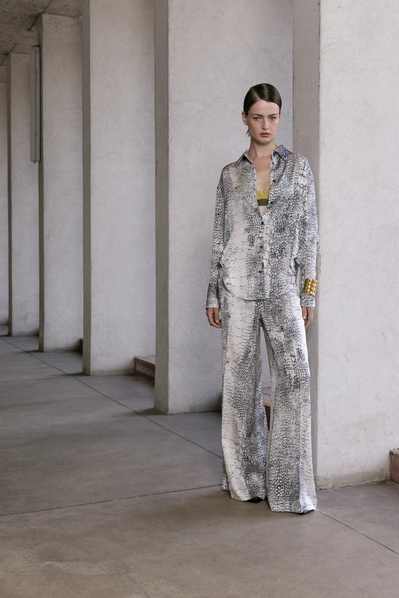 Model wearing a patterned outfit standing against a neutral background.